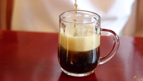 soda being poured, foam rising in mug