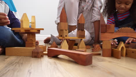 mother and children playing with building blocks in bedroom