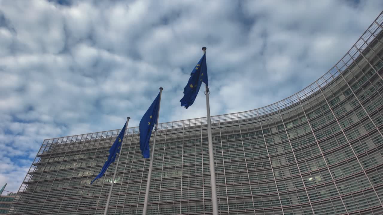 Slow motion of EU flags waving strongly outside Commission headquarters