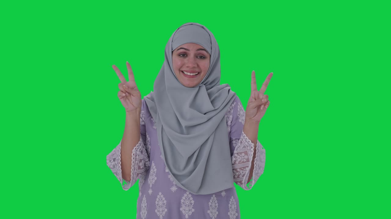 행복한 무슬림 여성이 승리의 표지판을 보여주는 녹색 화면
