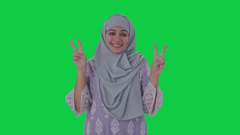 happy muslim woman showing victory sign green screen