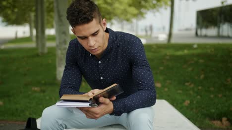 retrato bien vestido joven atractivo hombre de moda leyendo un libro viejo un parque urbano día soleado por la mañana