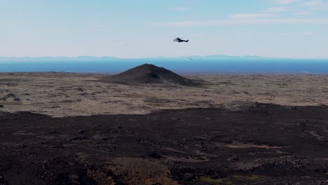 Search-and-rescue-helicopter-flying-past-black-basalt-rock-field-in-Iceland