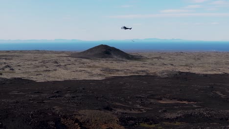 helicóptero de búsqueda y rescate volando por el campo de roca de basalto negro en islandia