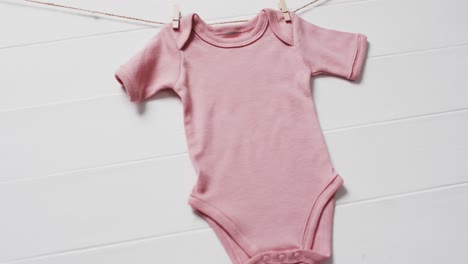 video of pink baby grow hanging on clothes begs on line with copy space on white background