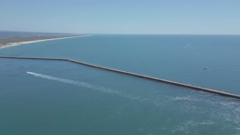 Vista-Aérea-Del-Barco-Acelerando-Hacia-La-Playa-De-Farol-En-Las-Tranquilas-Aguas-Del-Algarve-En-Un-Fantástico-Día-Soleado