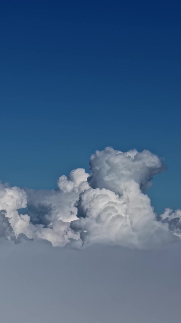 Rekaman drone vertikal di atas awan, pemandangan udara ketinggian tinggi formasi awan kumulus yang lembut di langit biru cerah