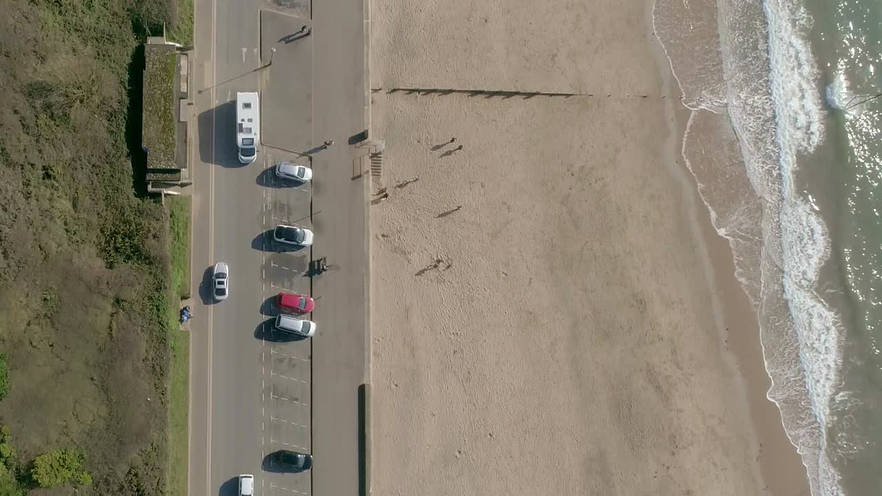 모래 해변과 탁한 바다 파도가 밀려오는 바쁜 도로의 위에서 아래로 공중