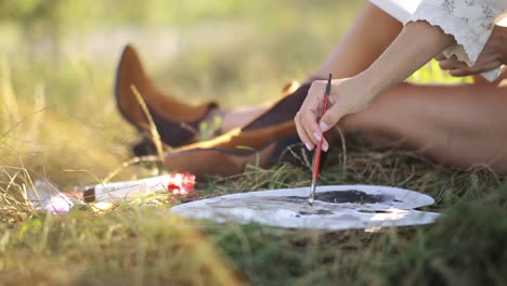 close-up of hand painting outdoors with palette and brush