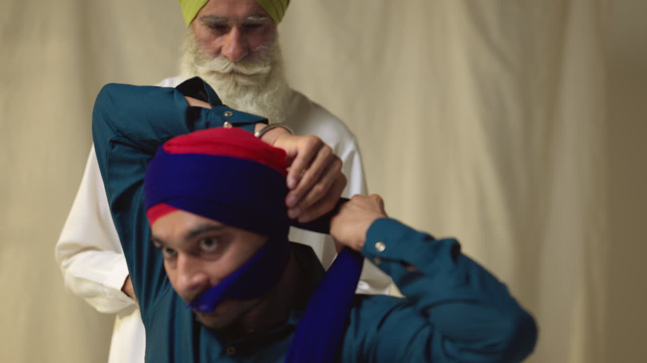 실시간으로 촬영 된 평평한 배경에 대한 을 는 젊은 sikh 남자를 돕는 고위 sikh 남자의 스튜디오  1