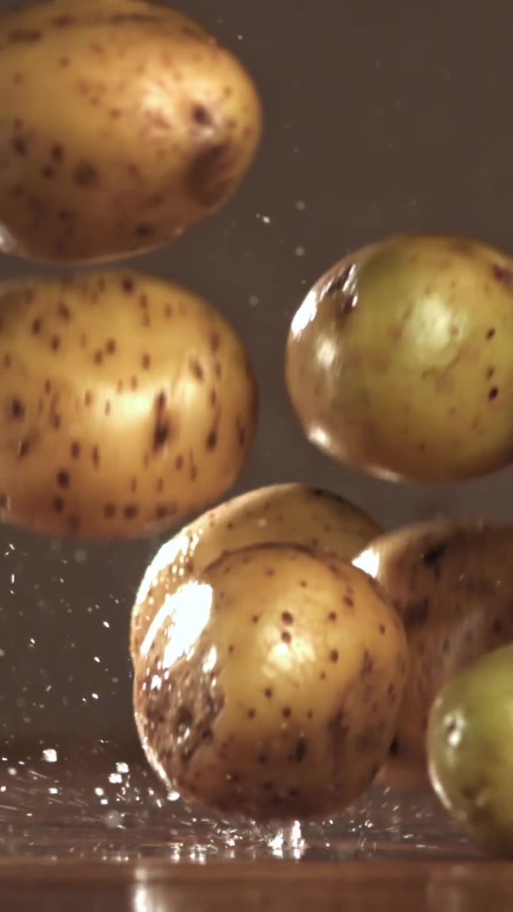 Patate fresche che cadono e schizzano acqua al rallentatore