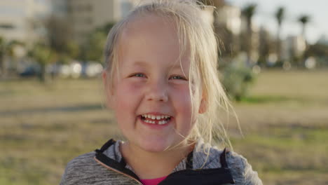 Primer-Plano-Retrato-Hermosa-Niña-Rubia-Sonriendo-Feliz-Disfrutando-De-Un-Relajado-Día-De-Verano-En-Un-Parque-Urbano-Al-Atardecer-En-Cámara-Lenta