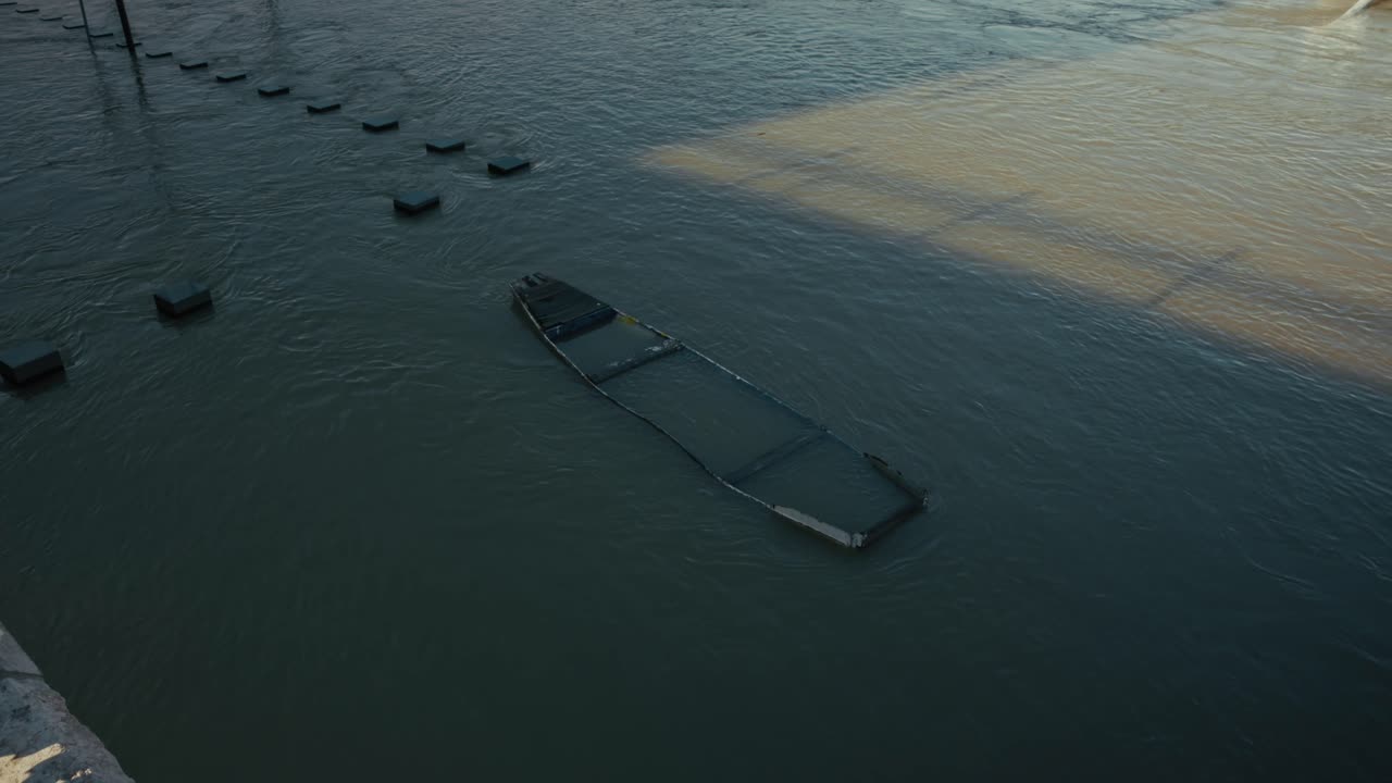 Submerged structure floating in murky floodwaters under shadowy light, Budapest, Hungary