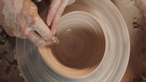 pottery artist shaping a bowl on a pottery wheel