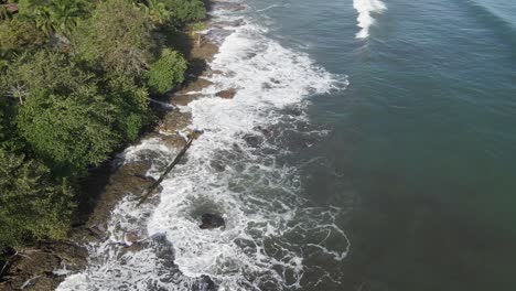 waves landing on island with green trees during high tide