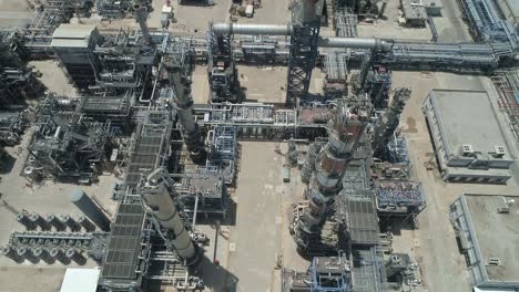 aerial footage of a large scale oil refinery with smoke stacks and petroleum storage tanks