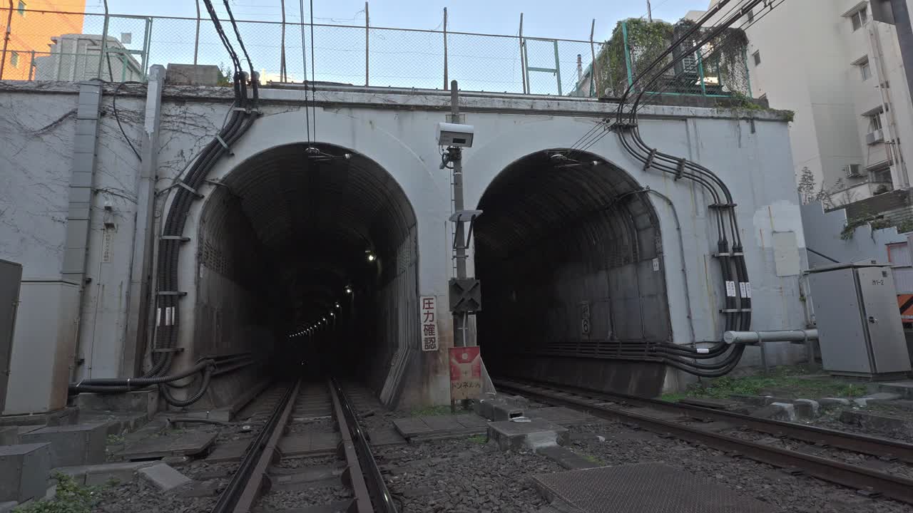 Two parallel train tunnels and tracks lead into the distance, conveying a sense of urban infrastructure and transit in Tokyo, Japan.