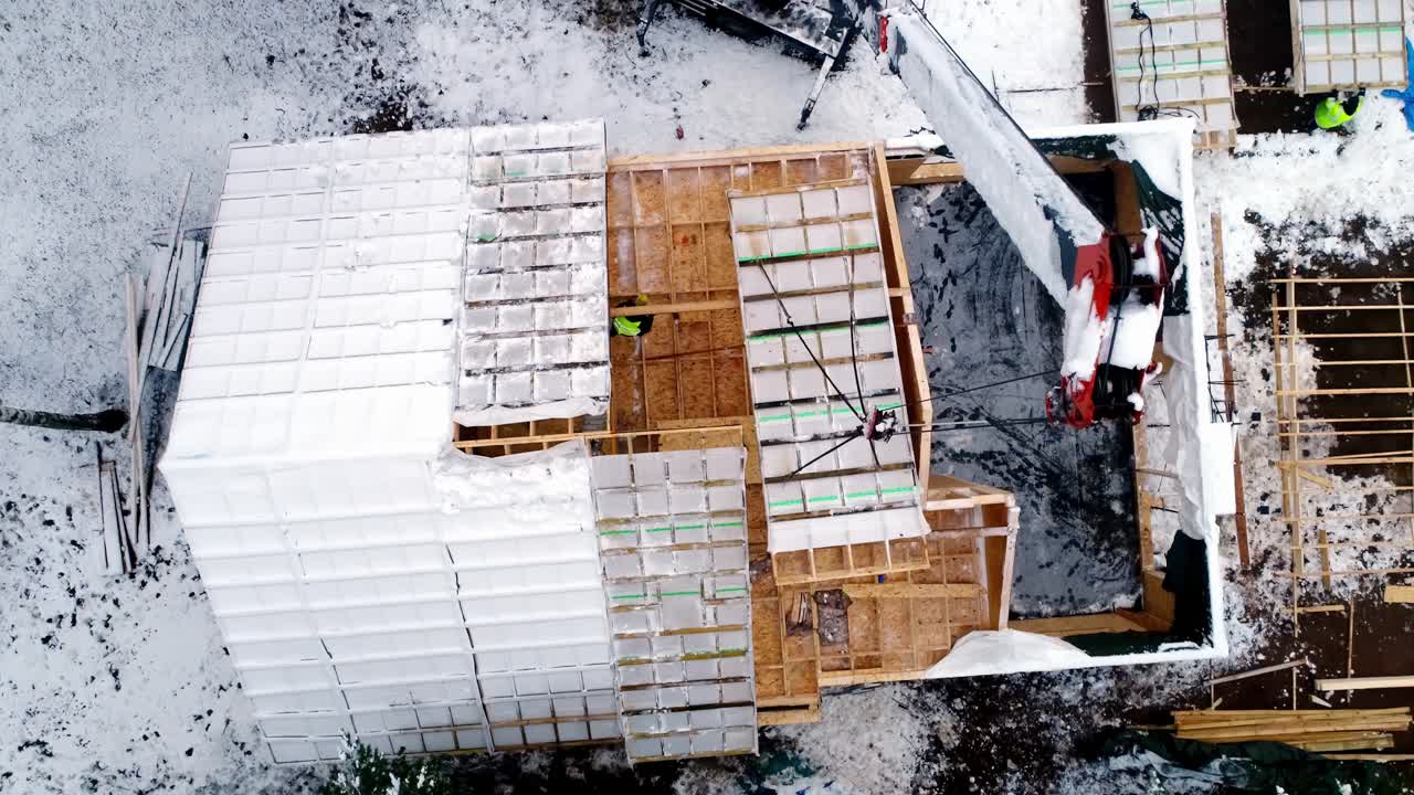 Aerial view of construction site with crane lifting materials in snow