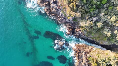 Breathtaking-Aerial-View-of-a-Pristine-Turquoise-Cove-Surrounded-by-Rugged-Coastal-Terrain-and-Lush-Greenery