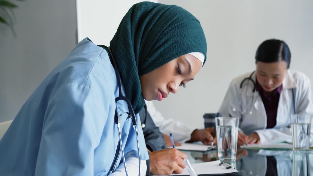 молодые врачи сидят за столом и пишут 4к.