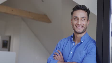 Happy-biracial-man-standing-in-living-room,-leaning-and-looking-out-of-window,-slow-motion