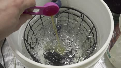 pouring a scoop of chemicals in water for plant food -slow motion