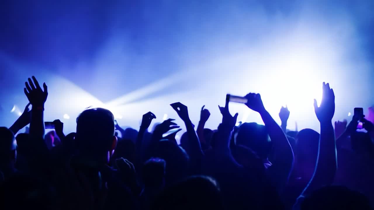 los miembros de la audiencia aplauden y filman una banda actuando en el escenario, iluminada por luces azules vibrantes durante un animado concierto