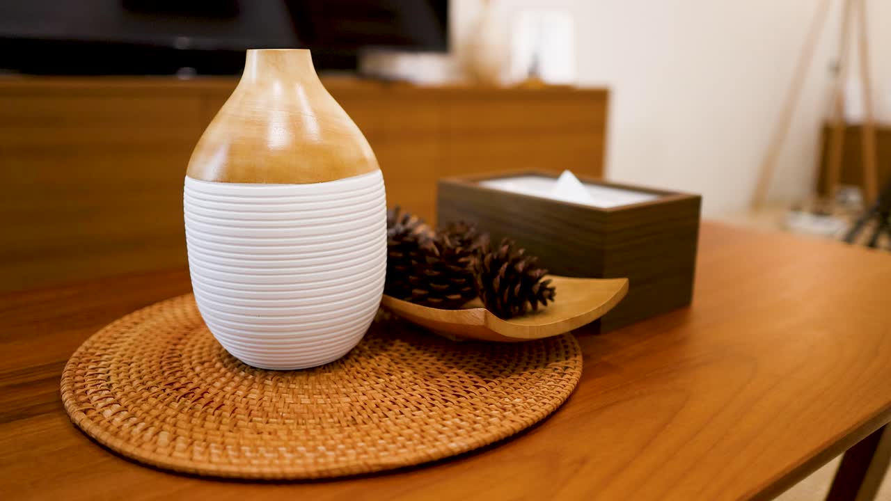 Une main retire un panneau métallique "interdit de fumer" d'une table avec un diffuseur d'aromathérapie