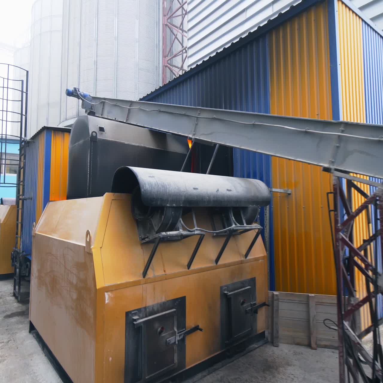 Huge hangar premises for storage and processing crops. Oncoming to the premise with burning fire inside. Modern industrial factory exterior