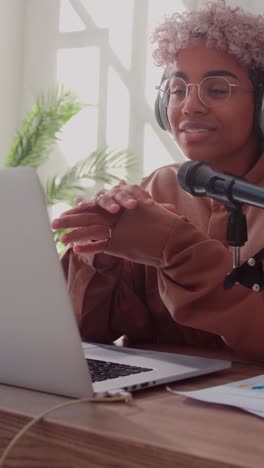 young african american woman hosts audio podcast sits at table with microphone