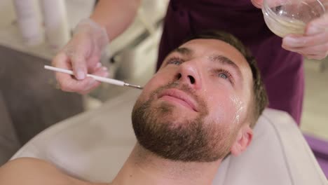 man receiving facial treatment at spa