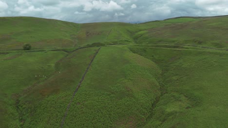 Drone-shot-of-green-hills-revealing-mountains-at-background-in-England