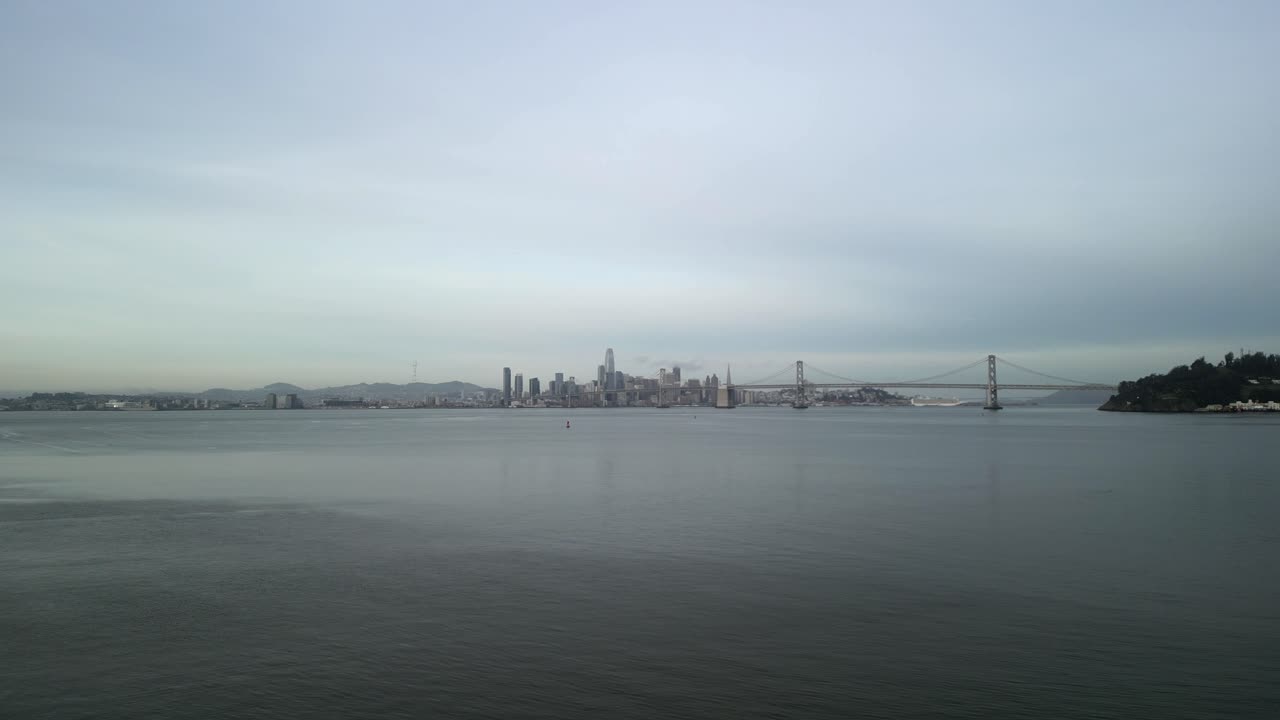 The San Francisco Bay Bridge stands as a gateway for commuters and trade, seen from above in crisp drone footage.