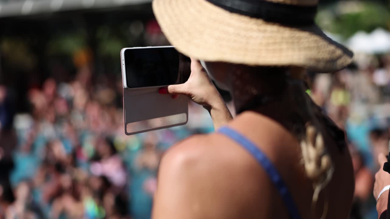Woman taking pictures with her phone in a crowd