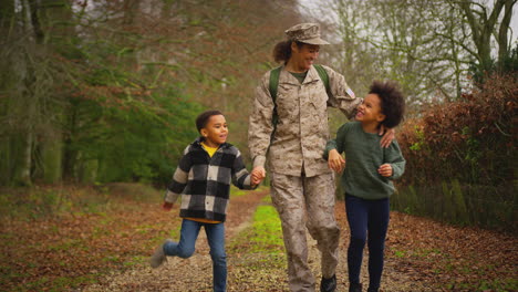 american female soldier returning home on leave to family walking with two children holding hands