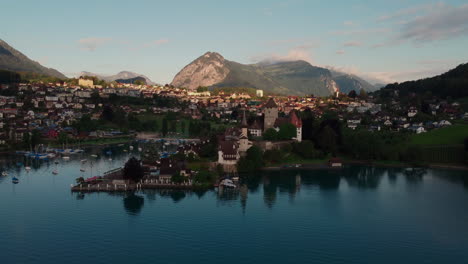 Aerial-overview-orbiting-around-the-medieval-castle,-schloss-Spiez-on-the-shore-of-lake-Thun