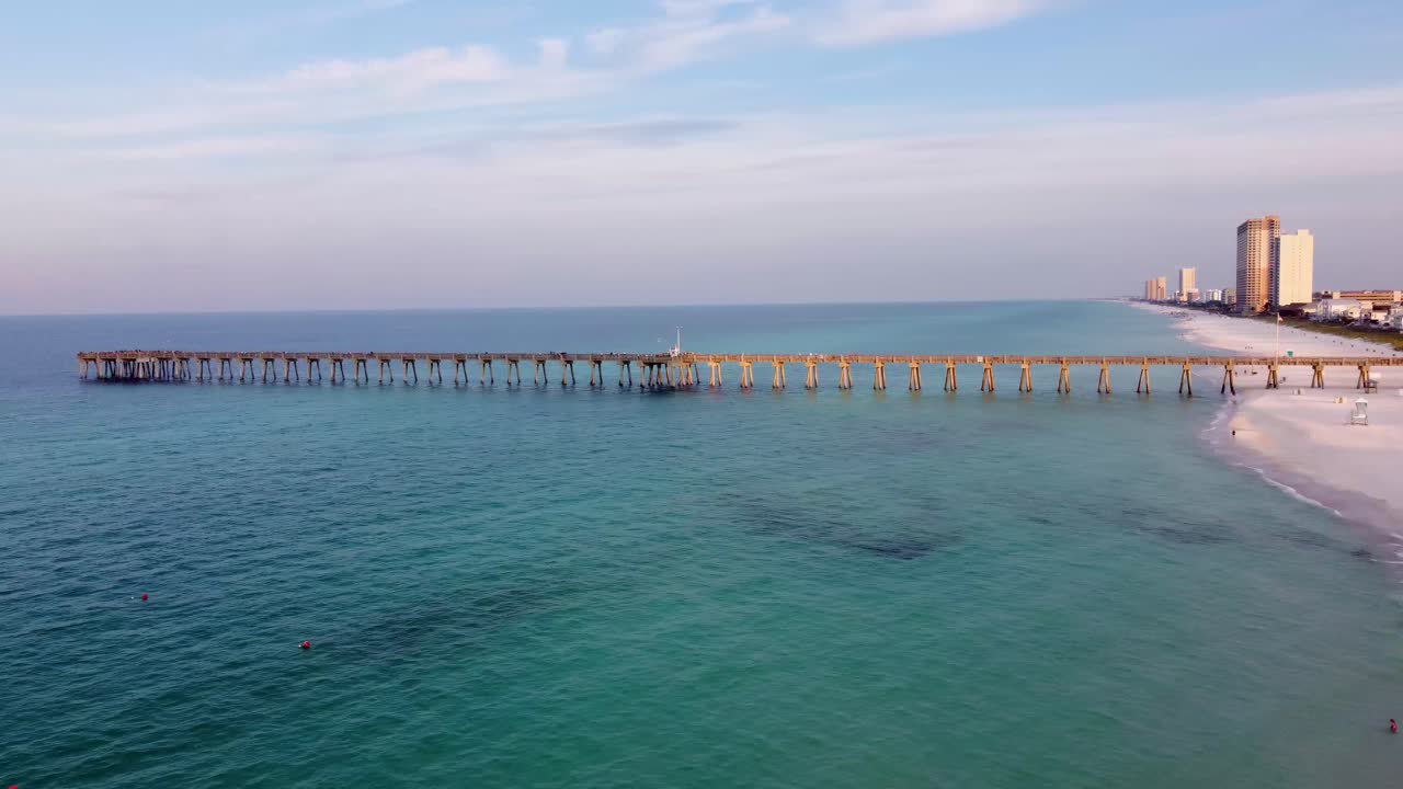 Aerial shot of the silhouette of a fishing pier on the ocean with a colorful and golden sunrise