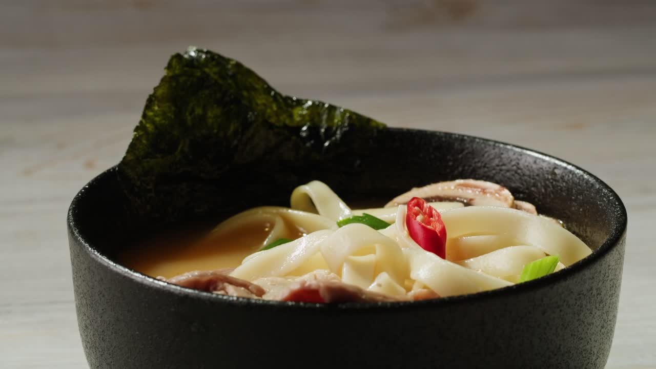 una mujer comiendo un plato de ramen.