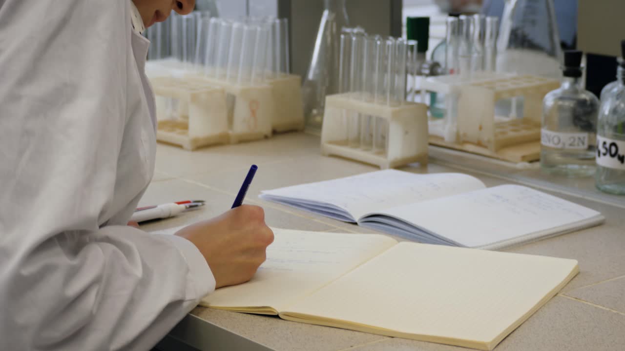 científico escribiendo en un cuaderno de laboratorio