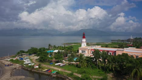 A stunning drone shot showcases a towering lighthouse standing against a clear blue sky, overlooking the serene shores and endless ocean.