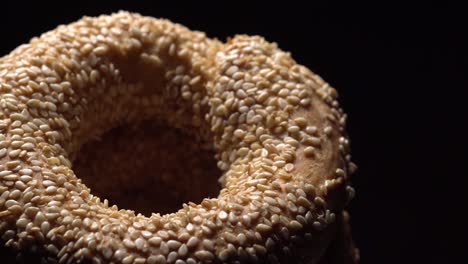 fresh bagels with sesame seeds in rotation. black background. extreme closeup.