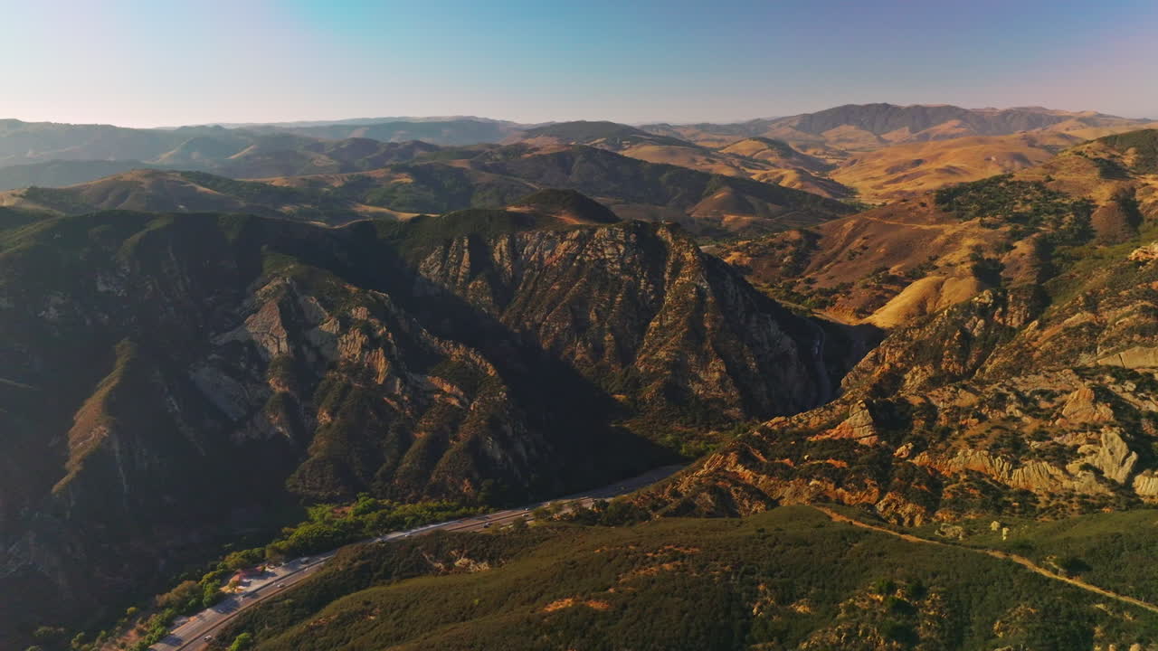 Beautiful mountainous landscape on sunny day somewhere in United States. Road going through the mountains with many cars. Aerial view.