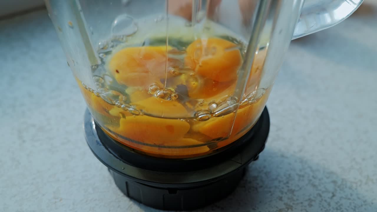 Vista macro statica che cattura un uovo crudo che cade in un frullatore in condizioni di luce diurna