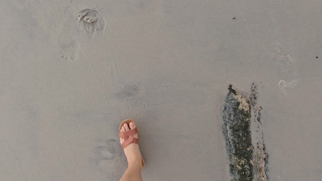 Person walking barefoot on sandy beach