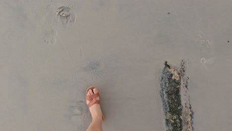 person walking barefoot on sandy beach