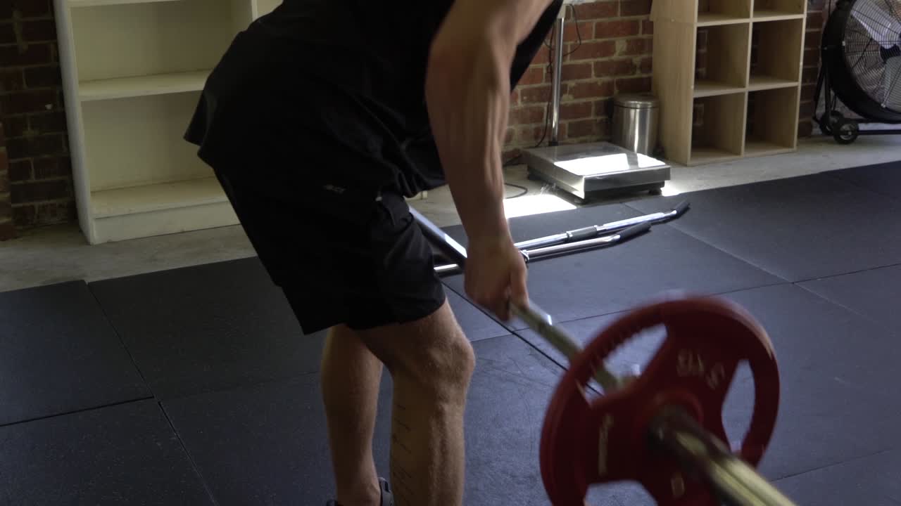 Muscly man in home gym exercising close grip barbell row