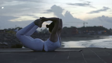 Woman-In-White-Sportswear-Doing-A-Yoga-Posture-On-The-Beach