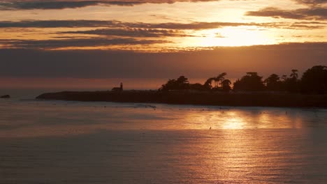 Sunset-aerial-view-of-surfers-outside-of-santa-cruz,-california-during-golden-hour