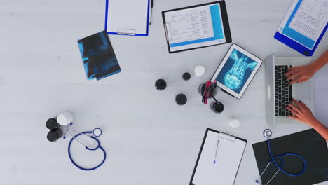 vista superior de las manos del médico escribiendo en la computadora portátil