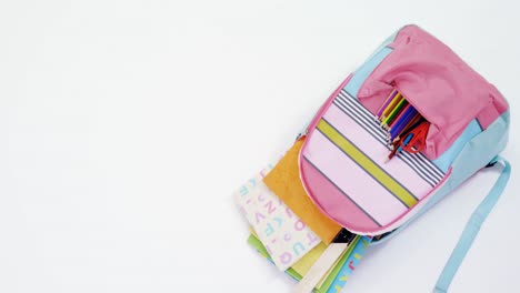 schoolbag with supplies on white background